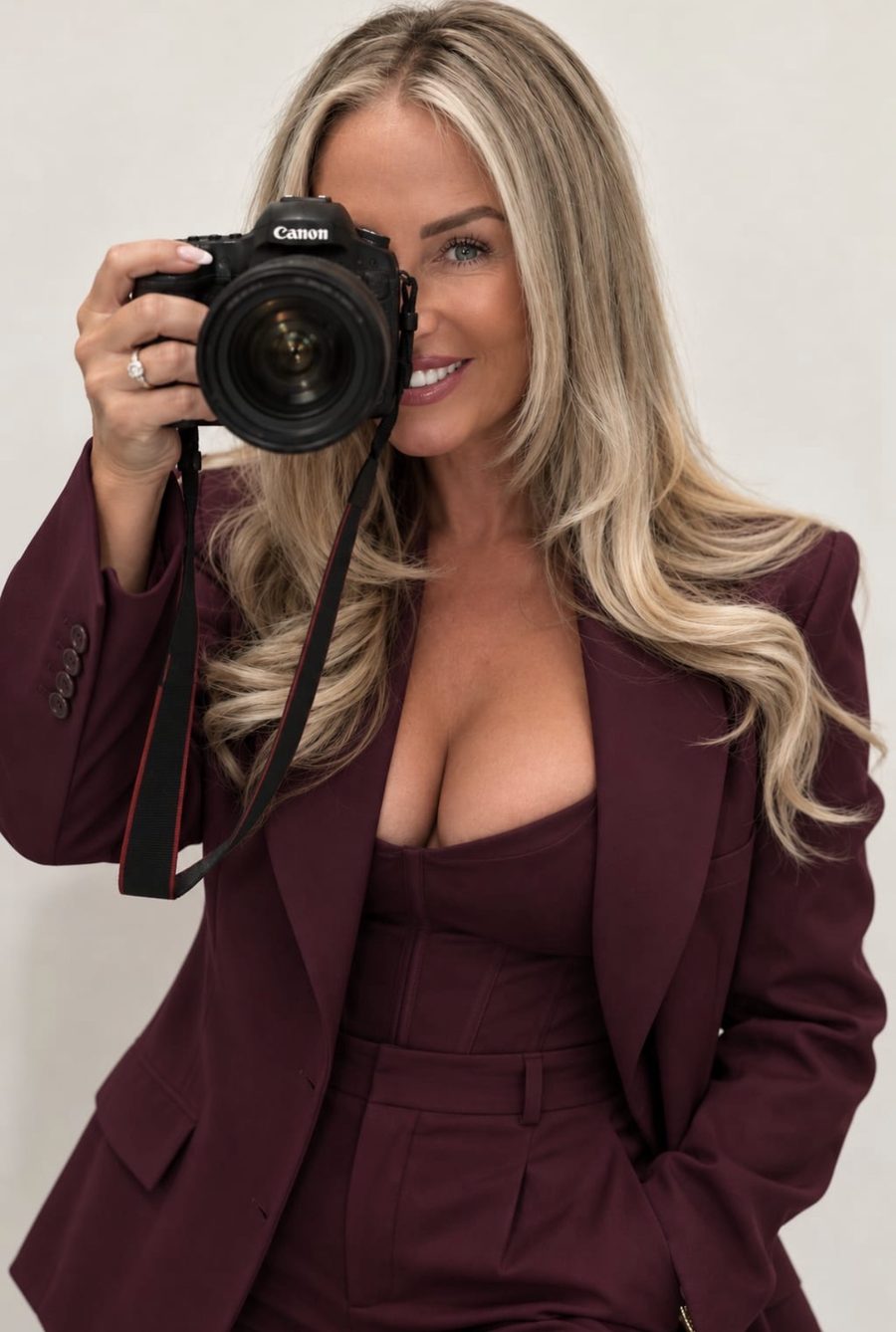 Chelsea, founder of PAPPED, holding a Canon camera up to one eye and smiling